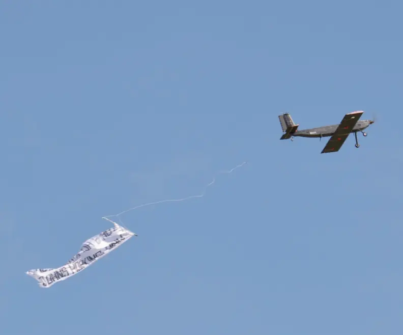The aircraft in flight towing its competition banner